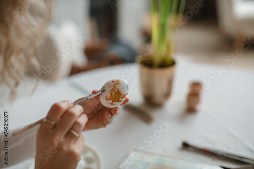 Close-up of a woman sitting at a dining table decorating an Easter Egg photo