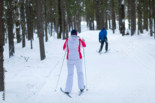 People ski in winter on a ski track through a winter forest.Cross Country skiing.