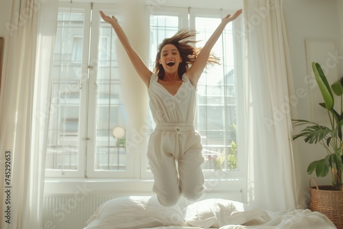 Wallpaper Mural Happy woman jumping on bed, bright room, sunlight from window, lively morning Torontodigital.ca