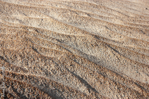 Waves on the surface of the sand, top view. The wavy surface of coastal sand. The structure of waves on sea sand.