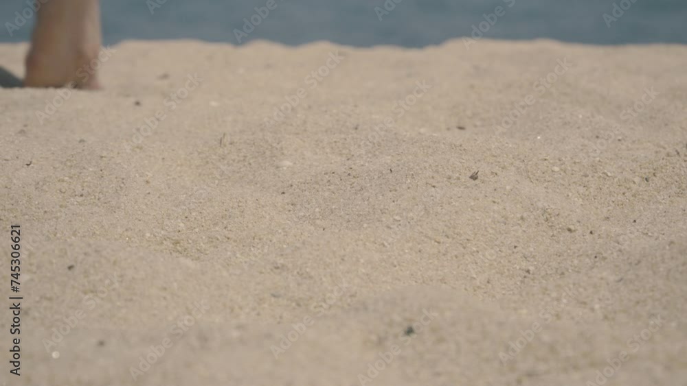 A man walks barefoot on the sand on the beach in the direction away from the camera A man walks barefoot on the sand on the beach in the direction away from the camera