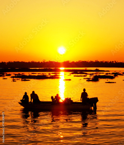 Group of fishermen in boat in back light at sunset