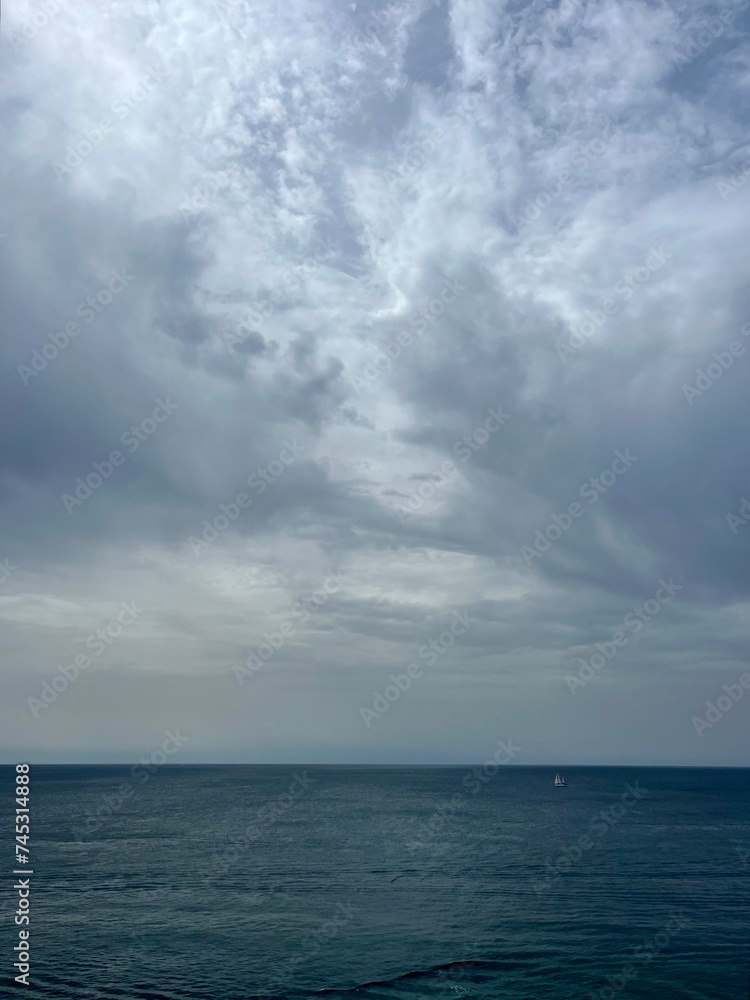 Cloudy seascape, sail boats silhouettes at the sea