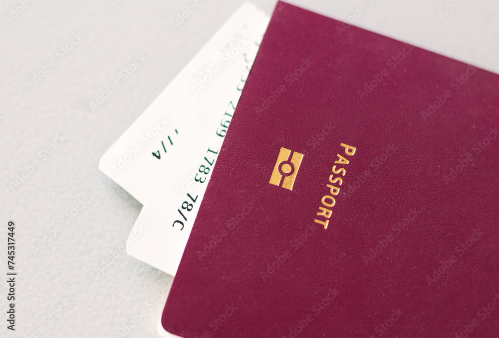 Close up of burgundy passport with flight ticket on grey background. Immigration and travel concept Close up of burgundy passport with flight ticket on grey background. Immigration and travel concept