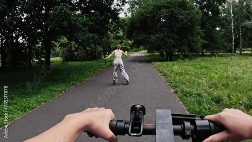 Young woman riding electric scooter with rollerscating teenager girl in park. Friends with modern vehicles enjoying outdoors activities at summer photo