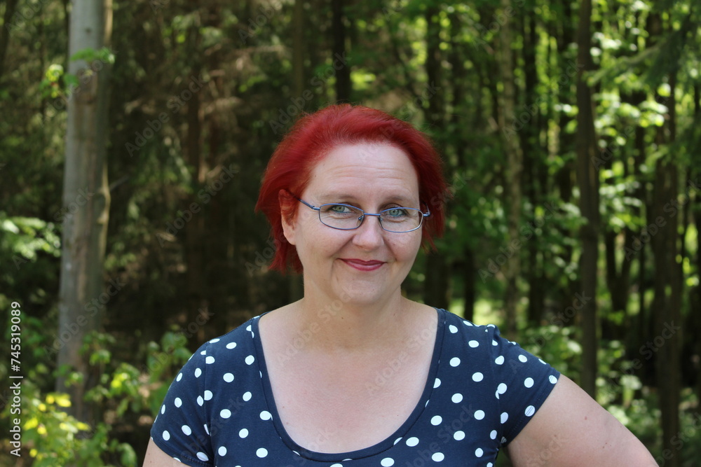 Portrait of a red-haired cheerful woman in the forest on a beautiful sunny summer day Portrait of a red-haired cheerful woman in the forest on a beautiful sunny summer day