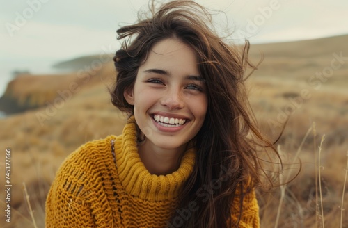 young woman dressed in yellow sweater laughing in front of camera