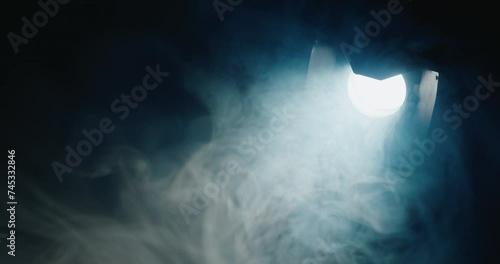 In the darkness, a potent directional light pierces through, illuminating swirling fog within its beam.