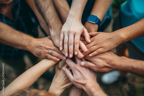 Close-up of a diverse group of hands stacked together in a show of unity and teamwork, symbolizing collaboration and cooperation.