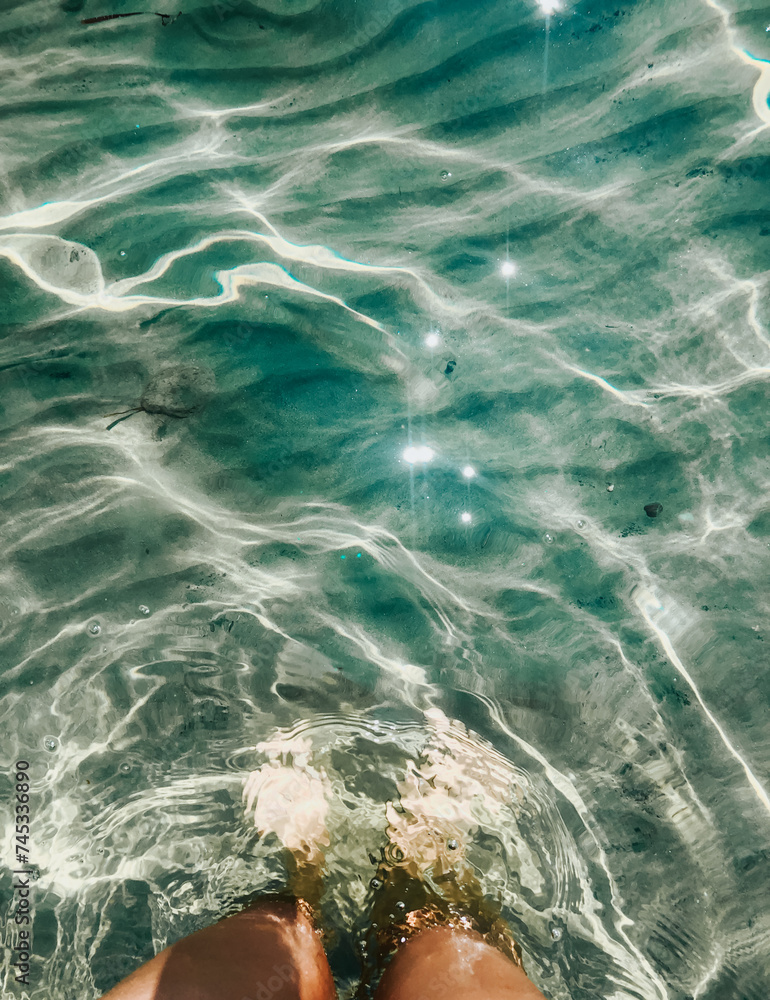 Woman legs barefoot at sea waves stones beach summer. top view above women feet.