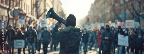 activist protesting with megaphone during a strike with group of demonstrators all around, demanding social justice and change © CinimaticWorks