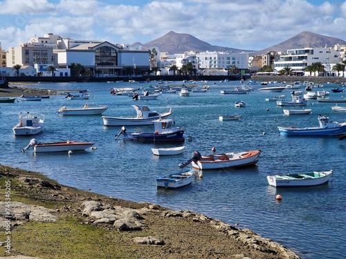
Colorful little fishing boats in the harbor of Arrecife, Lanzarote, Canary Island, Spain - volcano or mountain in the background photo