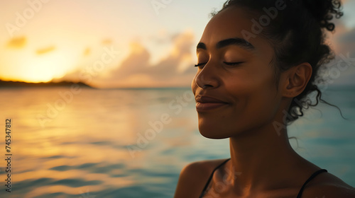 Jovem serena praticando yoga em uma praia isolada ao pôr do sol com o oceano ao fundo © Alexandre