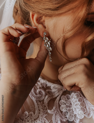 girl puts on big massive voluminous precious earrings in teams and stones