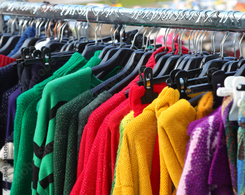 Colorful woolen sweaters hanging on hangers for sale in the open-air market in winter