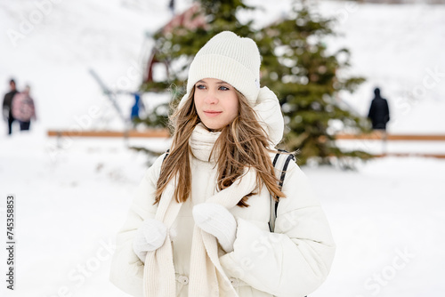 A charming young girl walks in the winter in the city park