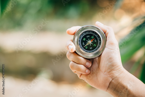 Hiker relies on compass to find direction in forest confusion. compass firmly held by traveler symbolizes leadership and exploration amidst nature helping her map position on journey of discovery.
