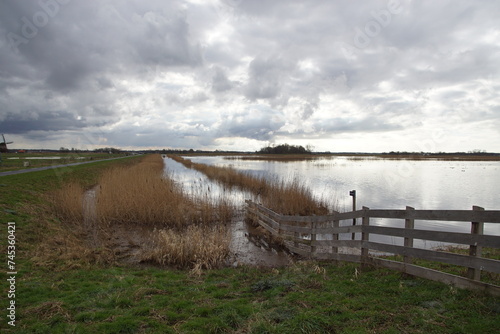 Ditch  meadows with much water from the rain. Dark clouds. Near the village of Bergen. Netherlands  February. Winter. Polder water storage at very high rain water. Partially flooded  North Holland