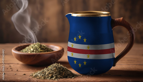 A teapot with the Cape Verde flag printed on it is on the table, next to it is a mug of tea and green tea is scattered. Concept of tea business, friendship, partnership