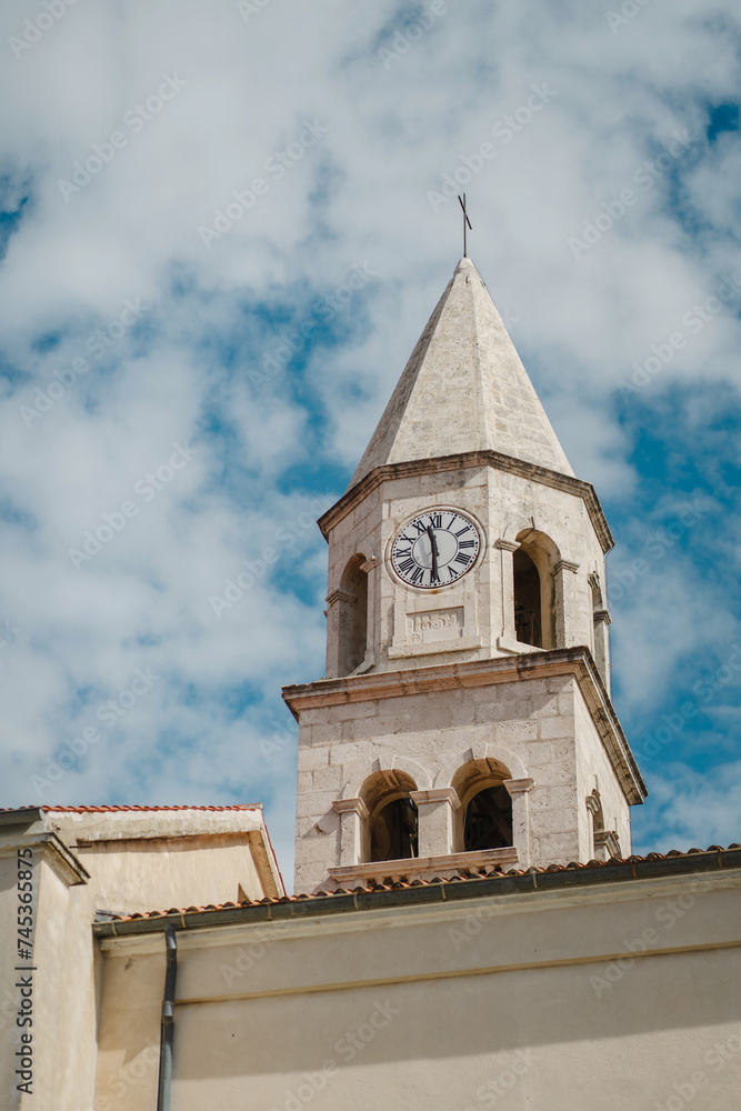 Ancient tower with vintage clock dial and cloudy blue sky in Old Town, Biograd na Moru in Croatia