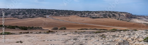 Panoramic landscape with winding asphalt road through hills and rocky lands in Cape Greco National Park, Cyprus