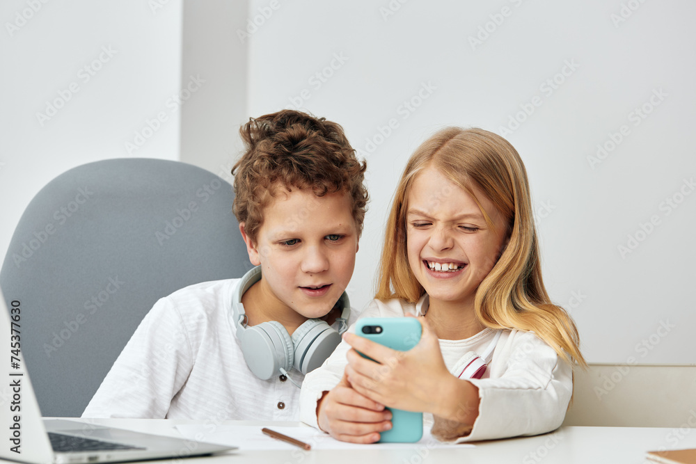 Happy Caucasian children studying and playing online with laptops and tablets at home Happy Caucasian children studying and playing online with laptops and tablets at home