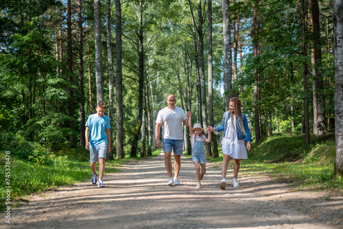 family enjoying a leisurely walk through a lush forest, ideal for quality time with family and bonding as well as kid and teenage insurance.