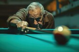 Elderly man playing pool on billiard table with cue stick