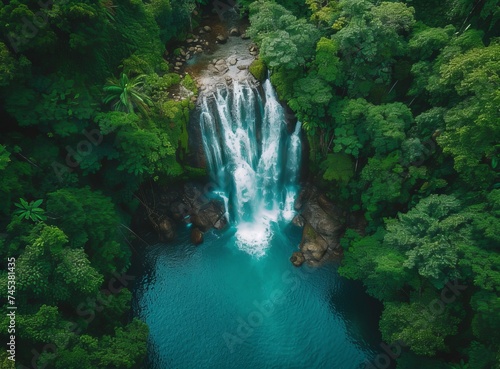 Aerial view of a serene waterfall amidst lush greenery, flowing into a tranquil turquoise pool.