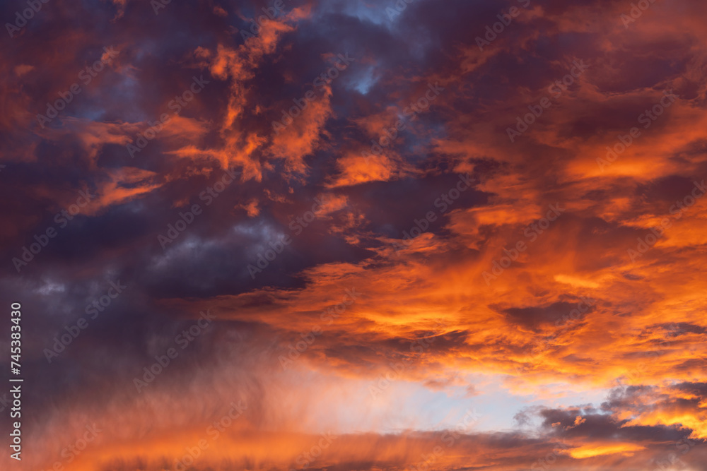 Dramatic fiery cloudy evening sky at sunset, clouds of bright colors in twilight