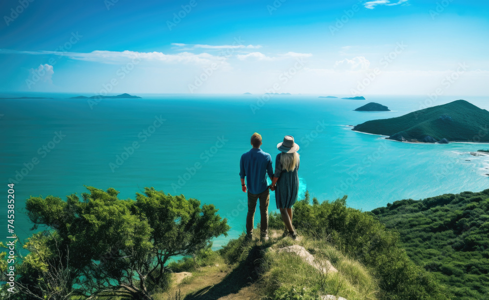 Two people standing on top of a hill overlooking the ocean.