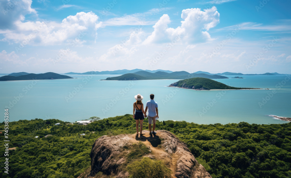 Two People Standing on Top of a Hill Overlooking the Ocean
