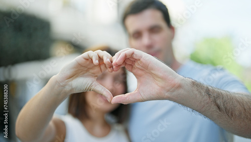 Beautiful couple smiling confident doing heart gesture with hands at street