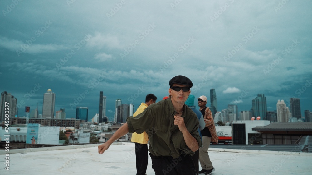 Closeup image of profession hipster dancing break dance at rooftop with multicultural friends. Break dancer practicing street dance while surrounded by partners. Hip-hop. Outdoor sport 2024. Endeavor.