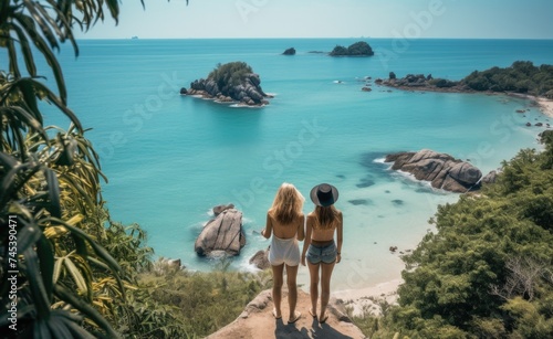 Two women standing on a cliff overlooking the ocean.