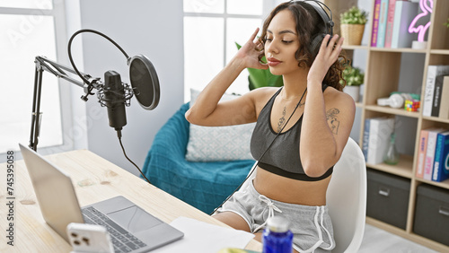 Young woman with headphones recording podcast in a modern studio interior, radiating creativity and professionalism.