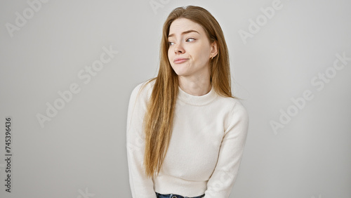 Portrait of a skeptical young woman with long blonde hair, wearing a white sweater against an isolated white background.