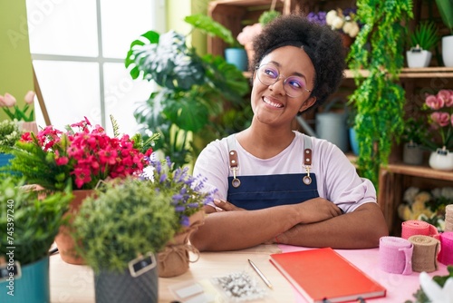 African american woman florist smiling confident sitting on table with arms crossed gesture at flower shop