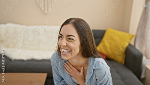 Heartwarming portrait of a young, beautiful hispanic woman, exuding confidence and joy, relaxing on her sofa at home, smiling off to the side