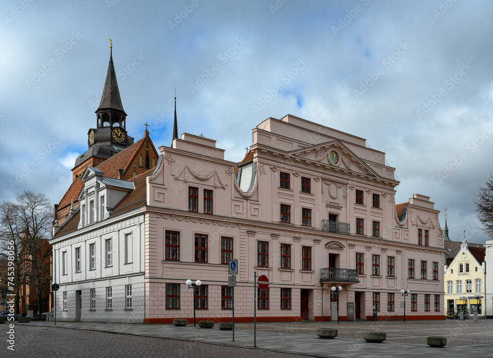 Mit Girlanden verzierte Schmuckfassade am Rathaus von Güstrow, dahinter der Turm der Pfarrkirche 