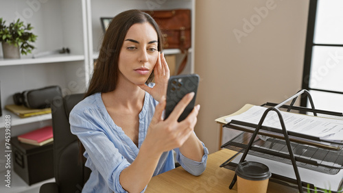 Young beautiful hispanic woman business worker using smartphone at the office