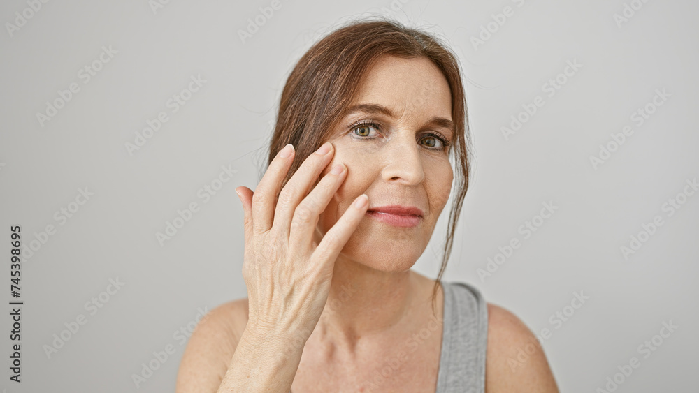 A middle-aged woman with short hair examines her complexion against a white background, highlighting her mature beauty. A middle-aged woman with short hair examines her complexion against a white background, highlighting her mature beauty.