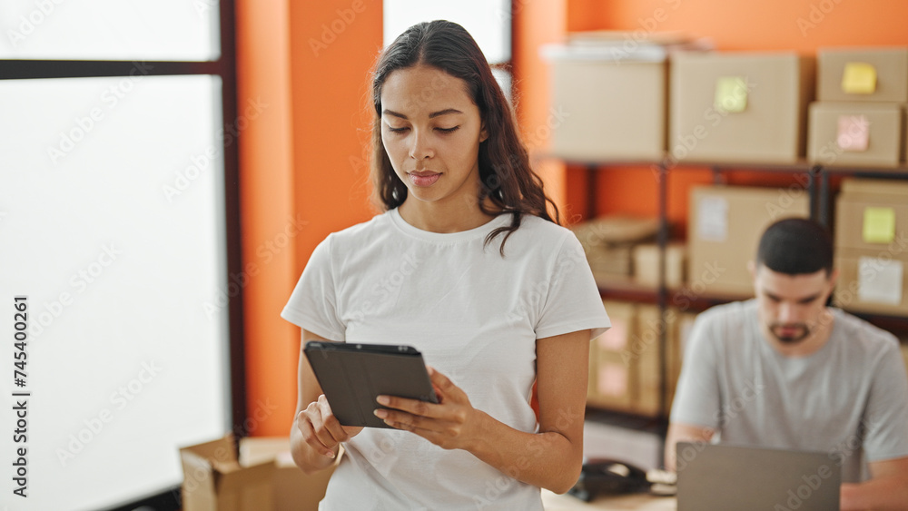 Two dynamic workers, a man and woman, working together in a relaxed office environment, using a laptop and touchpad, completing ecommerce orders in their shared workspace. Two dynamic workers, a man and woman, working together in a relaxed office environment, using a laptop and touchpad, completing ecommerce orders in their shared workspace.