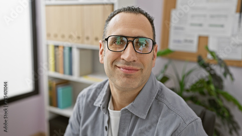 Smiling hispanic businessman wearing glasses in a modern office setting