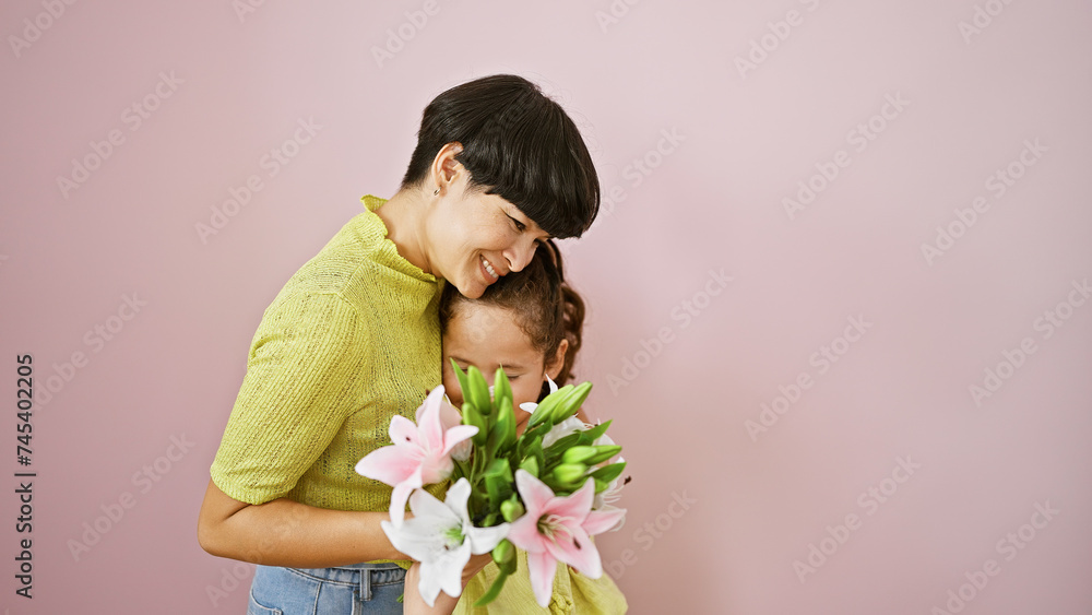 Over joyful mother-daughter hug with bouquet smiling on isolated pink background, an expression of family love and happiness Over joyful mother-daughter hug with bouquet smiling on isolated pink background, an expression of family love and happiness