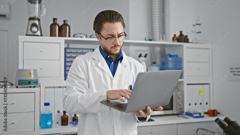 Young hispanic man scientist using laptop at laboratory