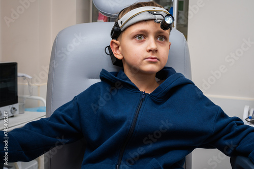 little emotional boy, fair-haired teenager, sitting in the otolaryngologist's office, waiting for the doctor for an examination, but smiling. Physical examination