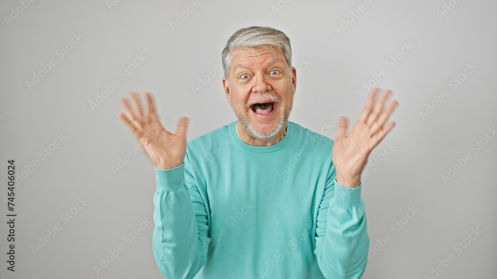 Surprised senior man with gray hair wearing a teal sweater isolated against a white background expressing excitement. Surprised senior man with gray hair wearing a teal sweater isolated against a white background expressing excitement.