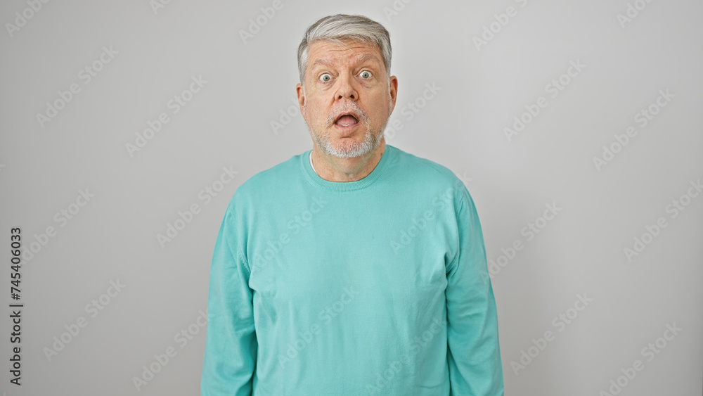 Surprised senior man with grey hair in a mint sweater against a white background looking at camera. Surprised senior man with grey hair in a mint sweater against a white background looking at camera.