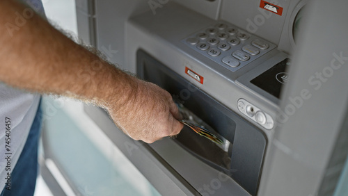 Fotografía Handsome middle-aged caucasian man holding australian dollars, caught mid-transaction at urban street atm